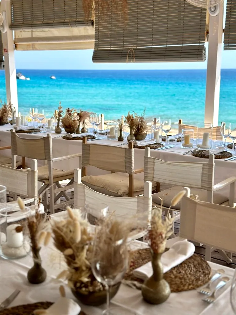 Tables with brass vases facing turquoise water